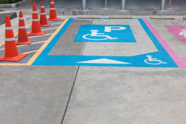 Engelli ya da tekerlekli sandalye park yeri. Park yerindeki engelliler için ayrılmış park yeri tabelası var. Uluslararası engelli sembolü bir alışveriş merkezinin park yerine açık maviyle boyanmış.. 