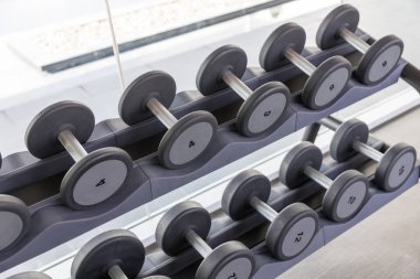 Aptal seti. Spor fitness merkezinde raflarda birçok metal dambıl var. Ağırlık Eğitimi Ekipmanı konsepti. Spor aletleri ağırlık kaldırıyor, egzersiz için. Spor salonundaki dambıllar.