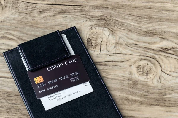 The black credit card on blank bill paper in  leather black bill receipt. Receipt Holder with credit card on cafe or Restaurant.