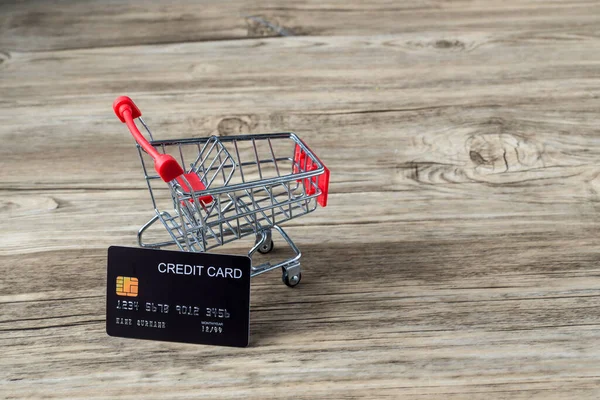 有信用卡的购物车 用信用卡的概念呆在家里购物和电子支付 里面装有信用卡的小购物车是桌上的生意 概念上是用信用卡购物的 — 图库照片