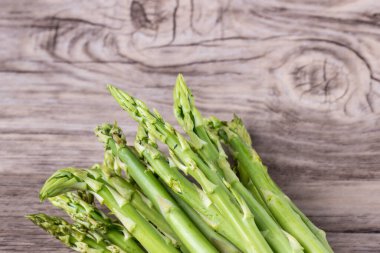 Taze kuşkonmaz. Pişirmeye hazır taze yeşil kuşkonmaz organik sebzeler. Ahşap arka planda bir grup taze kuşkonmaz. Sağlıklı aşçılar için çiğ sebze.