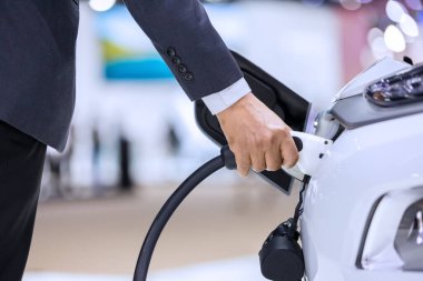 Elektrikli araba şarj aleti. Elektrikli Araç EV şarj istasyonu ve şarj aleti. İnsan eli, elektrikli araba şarjına bağlı..