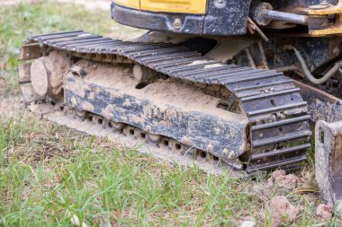 Kazı araçlarının izleri. Yoldaki traktörün buldozerinin eski demir tırtılları. Buldozer tırtıl izleri. Tekerlekleri yerde olan siyah tırtıl traktörü..