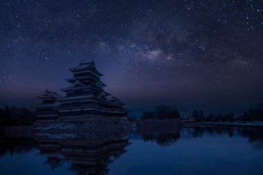 Japonya 'daki eski kale. Matsumoto kalesine karşı gece gökyüzü. Kışın Samanyolu 'nda gökyüzünde şato. Kışın donmuş göleti olan Matsumoto Kalesi' ni gezin. Japon başbakanı tarihi kaleler