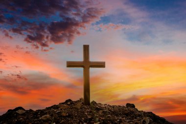 Gün batımının arka planında çapraz. Paskalya konsepti. Kavramsal siyah haç sembolünü çimenlerin üzerinde gün batımında ya da gün doğumunda gökyüzünde hayal et..