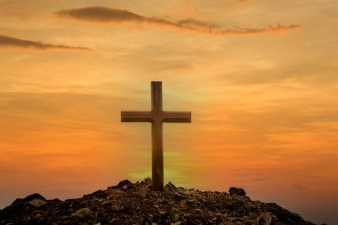 Gün batımının arka planında çapraz. Paskalya konsepti. Kavramsal siyah haç sembolünü çimenlerin üzerinde gün batımında ya da gün doğumunda gökyüzünde hayal et..