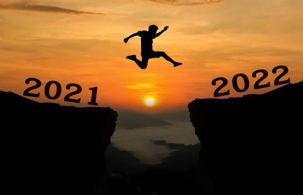 2021年至2022年之间 一个年轻人跳过太阳 穿过山丘轮廓的缝隙 夜晚的天空五彩斑斓 新的一年2022 — 图库照片