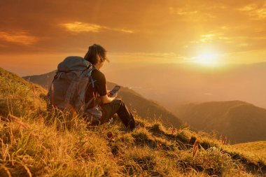 Gezgin kadın huzur dolu dağlarla meditasyon yapıyor. Dağın tepesinden manzaranın tadını çıkaran bir kız. Doğayla baş başa..