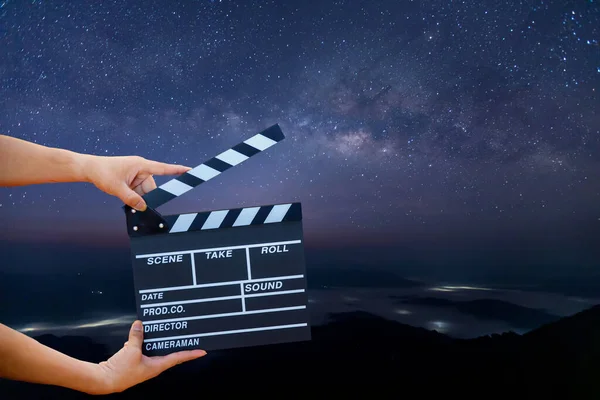 Man hands holding movie clapper on Milky Way , Stars and mountains. Shown slate board. use the colors white and black. Realistic movie clapperboard. Clapper board isolated. Film director concept.