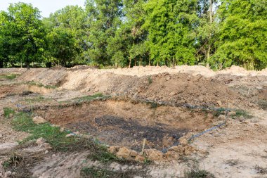 Toprakta bir delik. Fidanları dikmek için çukur kazın. Ağaç dikmek için çamur deliği. Topraktaki çukur manzarası ve bir gölet inşa etme hazırlığı. İnşaat için zeminde dikdörtgen çukur kazın.