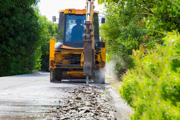 Excavator breaking and drilling the concrete road for repairing. Large pneumatic hammer mounted on the hydraulic arm of a construction equipment. Construction Vehicles repairing road. drill jackhammer