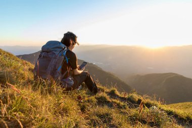 Gezgin kadın huzur dolu dağlarla meditasyon yapıyor. Dağın tepesinden manzaranın tadını çıkaran bir kız. Doğayla baş başa..