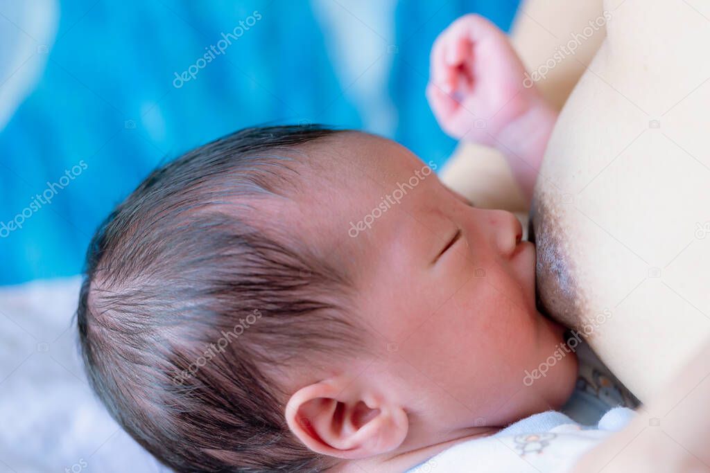 Woman breast feeding her baby on light background. mother holding her newborn child. Mom nursing baby. Woman and new born boy in white bedroom . mother feeding breast her baby at home .