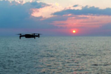 Dijital kamerayla uçan İHA helikopter. Yüksek çözünürlüklü dijital kameralı İHA. Uçan kamera bir fotoğraf ve video çek. Profesyonel kameralı İHA gökyüzünün ve denizin fotoğraflarını çekiyor..