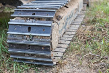 Kazı araçlarının izleri. Yoldaki traktörün buldozerinin eski demir tırtılları. Buldozer tırtıl izleri. Tekerlekleri yerde olan siyah tırtıl traktörü..