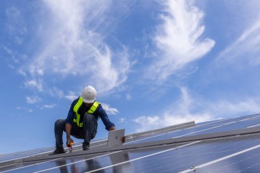 Fabrikanın çatısındaki güneş pilini kontrol et. Çatıda yürüyen mühendisler güneş pili panelini inceleyip kontrol ediyorlar. Çatıda çalışan mühendis teftiş kurulum güneş hücresi