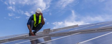 Fabrikanın çatısındaki güneş pilini kontrol et. Çatıda yürüyen mühendisler güneş pili panelini inceleyip kontrol ediyorlar. Çatıda çalışan mühendis teftiş kurulum güneş hücresi