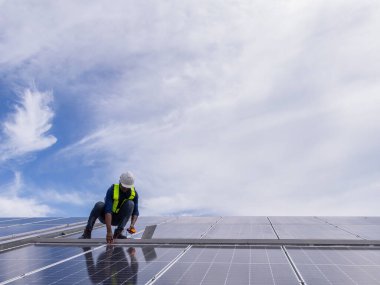 Fabrikanın çatısındaki güneş pilini kontrol et. Çatıda yürüyen mühendisler güneş pili panelini inceleyip kontrol ediyorlar. Çatıda çalışan mühendis teftiş kurulum güneş hücresi