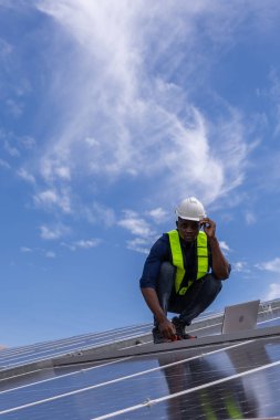 Fabrikanın çatısındaki güneş pilini kontrol et. Çatıda yürüyen mühendisler güneş pili panelini inceleyip kontrol ediyorlar. Çatıda çalışan mühendis teftiş kurulum güneş hücresi