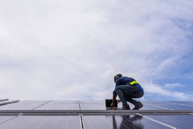 Fabrikanın çatısındaki güneş pilini kontrol et. Çatıda yürüyen mühendisler güneş pili panelini inceleyip kontrol ediyorlar. Çatıda çalışan mühendis teftiş kurulum güneş hücresi