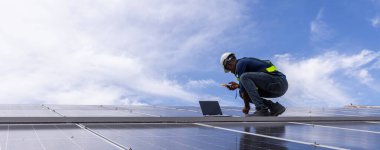 Fabrikanın çatısındaki güneş pilini kontrol et. Çatıda yürüyen mühendisler güneş pili panelini inceleyip kontrol ediyorlar. Çatıda çalışan mühendis teftiş kurulum güneş hücresi