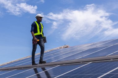 Fabrikanın çatısındaki güneş pilini kontrol et. Çatıda yürüyen mühendisler güneş pili panelini inceleyip kontrol ediyorlar. Çatıda çalışan mühendis teftiş kurulum güneş hücresi