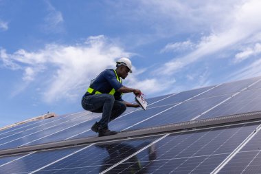 Fabrikanın çatısındaki güneş pilini kontrol et. Çatıda yürüyen mühendisler güneş pili panelini inceleyip kontrol ediyorlar. Çatıda çalışan mühendis teftiş kurulum güneş hücresi