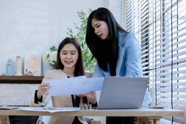 Ortaklardan oluşan bir grup Asyalı iş kadını dizüstü bilgisayarla ofiste projeyi tartışıyor. Profesyonel iş adamlarının iki meslektaşı birlikte çalışıyor..