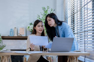 Ortaklardan oluşan bir grup Asyalı iş kadını dizüstü bilgisayarla ofiste projeyi tartışıyor. Profesyonel iş adamlarının iki meslektaşı birlikte çalışıyor..