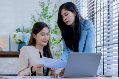 Ortaklardan oluşan bir grup Asyalı iş kadını dizüstü bilgisayarla ofiste projeyi tartışıyor. Profesyonel iş adamlarının iki meslektaşı birlikte çalışıyor..