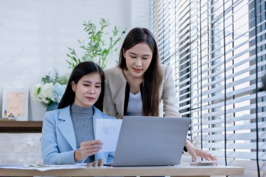 Ortaklardan oluşan bir grup Asyalı iş kadını dizüstü bilgisayarla ofiste projeyi tartışıyor. Profesyonel iş adamlarının iki meslektaşı birlikte çalışıyor..