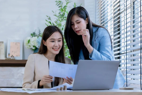 Ortaklardan oluşan bir grup Asyalı iş kadını dizüstü bilgisayarla ofiste projeyi tartışıyor. Profesyonel iş adamlarının iki meslektaşı birlikte çalışıyor..