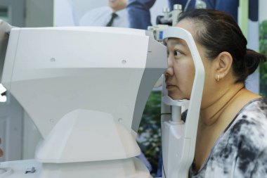 Göz testi için Phoropter, optik mağazada gözlük için gözlük. Göz uzmanı klinik muayenesi sırasında genç bayan hastaya kesik lamba ile detaylı göz kontrolü yapıyor..