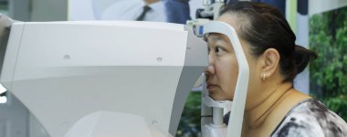 Göz testi için Phoropter, optik mağazada gözlük için gözlük. Göz uzmanı klinik muayenesi sırasında genç bayan hastaya kesik lamba ile detaylı göz kontrolü yapıyor..