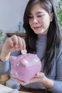 Kadın ev konseptinden çalışıyor. Muhasebe için para biriktiriyor. Tasarruf parası zenginlik kavramı, Asyalı iş kadını el yazısı yönetim bütçesi tasarruf maliyeti, nakit finans