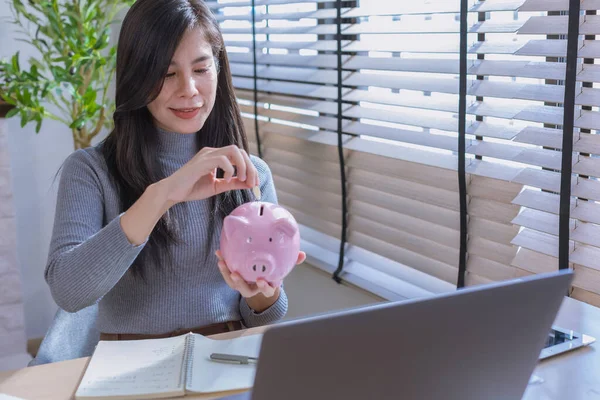 Kadın ev konseptinden çalışıyor. Muhasebe için para biriktiriyor. Tasarruf parası zenginlik kavramı, Asyalı iş kadını el yazısı yönetim bütçesi tasarruf maliyeti, nakit finans