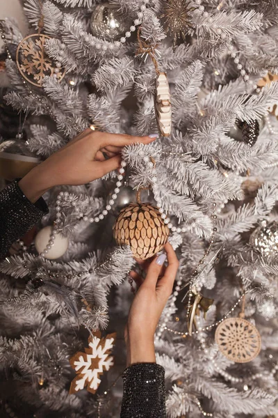 在圣诞树上切下的女人的手装饰和挂在树上的灌木 圣诞树背景图像 图库照片
