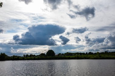 Göldeki renkli bahar manzarası. Güneşli bir gün, gökyüzünde bir sürü bulut. Gün doğumunda göl manzarası