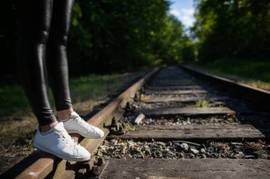 Düzgün genç bacaklar demiryolunda siyah tayt giyerek yürür..