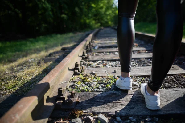 Patas adolescentes bien formadas caminan sobre rieles de ferrocarril con leggins negros. —  Fotos de Stock