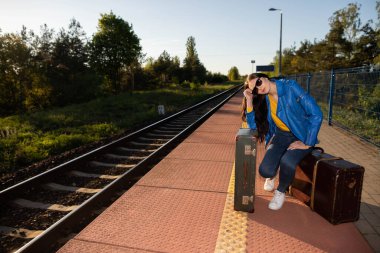 Sıkılmış bir genç, Güney Avrupa 'daki yaz tatilinde çok gecikmiş bir treni tren istasyonunda bekliyor..