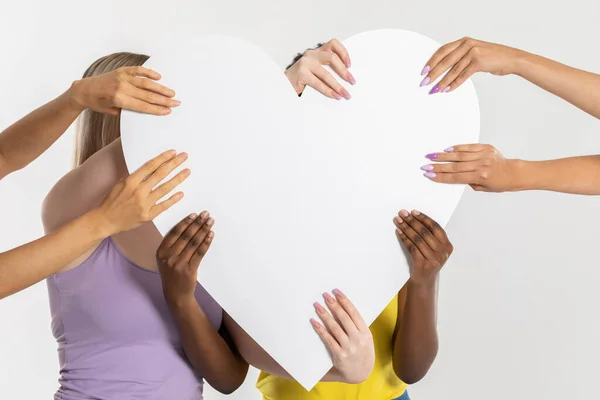 Un grand cœur blanc tenu par huit mains colorées de différentes nations et races. Beaucoup de races mais un cœur pur commun. — Photo