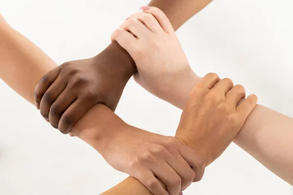 Elk van de vier handen is geklemd rond de pols van de vrienden. De ene hand grijpt de andere, enzovoort. Jonge meisjes handen. — Stockfoto