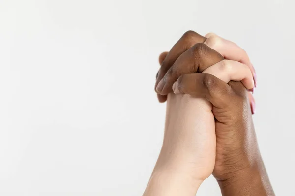 Clasped hands of two girls in love raised up. Handshake. Two women holding hands. African and European.