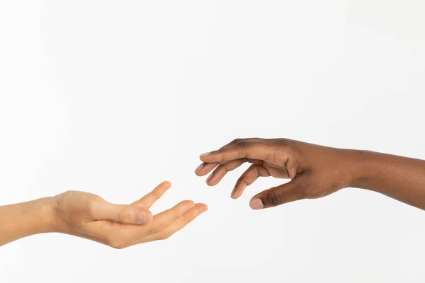 Destek olmak için uzatılmış bir el. İki el birbirine yaklaşıyor. İki ırkın elleri, Afrikalı ve Avrupalı, birbirlerini cezbediyorlar.. — Stok fotoğraf