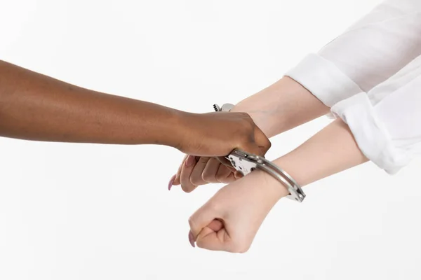 Un puño cerrado. Dos manos femeninas esposadas. Dos razas humanas conectadas por esposas de acero. Detención de los culpables. — Foto de Stock