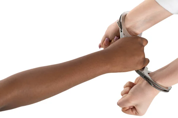 A clenched fist. Two female hands handcuffed. Two human races connected by steel handcuffs. Arrest of the guilty. — Stock Photo, Image