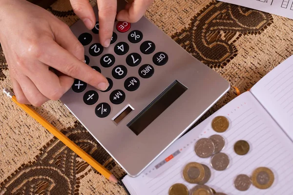 There are coins on the calendar and a young woman counts them because she wants to check if she has enough money to spend by the end of the month. — Stock Photo, Image