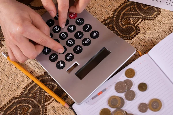 Auf dem Kalender stehen Münzen, und eine junge Frau zählt sie, weil sie prüfen will, ob sie bis Ende des Monats genug Geld hat, um es auszugeben.. — Stockfoto