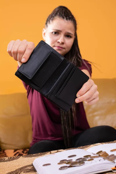 An adult teenager holds an empty wallet in her hands. Poor management of the household budget when one is very wasteful during everyday shopping. — Stock Photo, Image